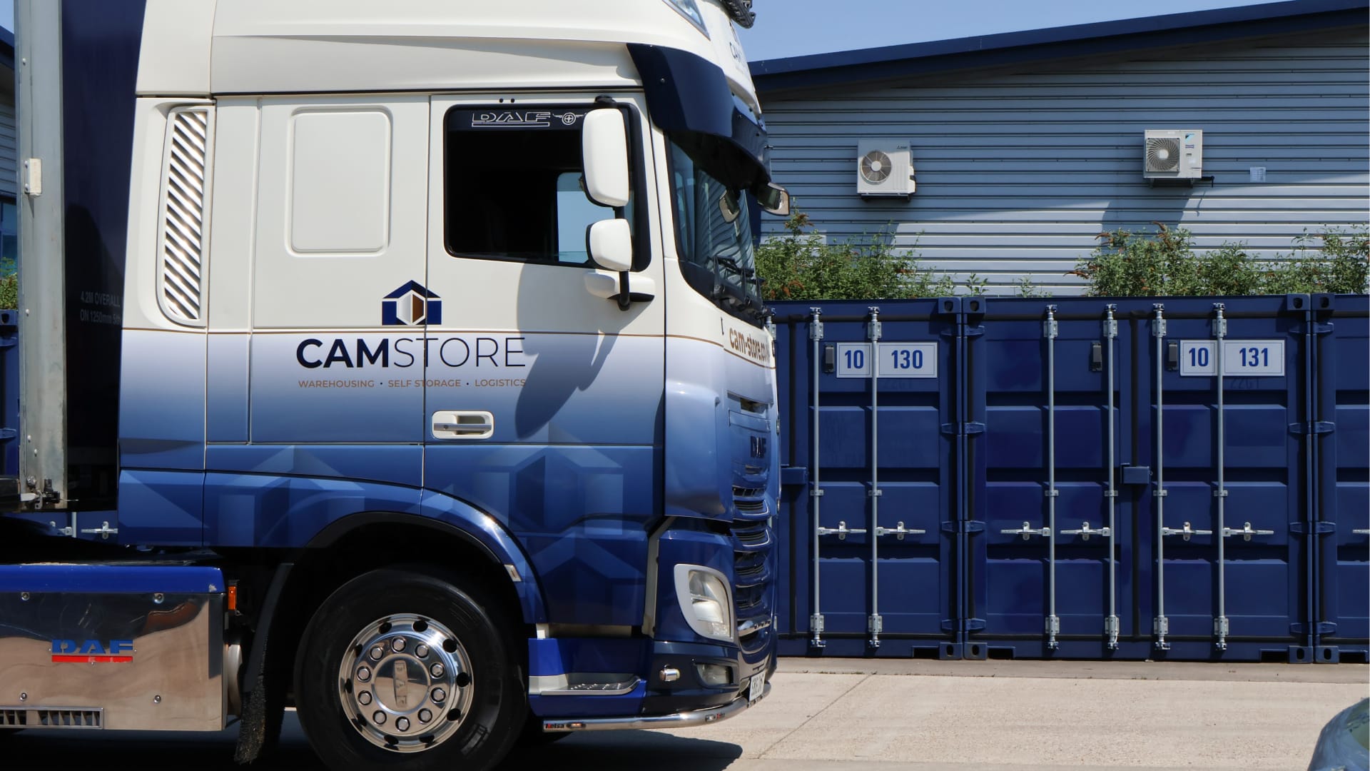 Cam Store lorry driving forward past self-storage containers.